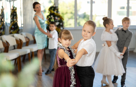 Little children practicing waltz dance in school-hall decorated with Christmas-treeの写真素材