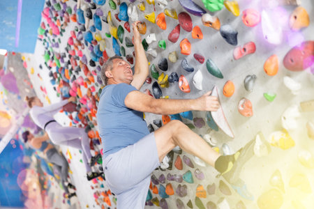 Male mountaineer climbing artificial rock wall without belay indoorsの写真素材
