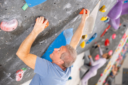 Male mountaineer climbing artificial rock wall without belay indoorsの写真素材