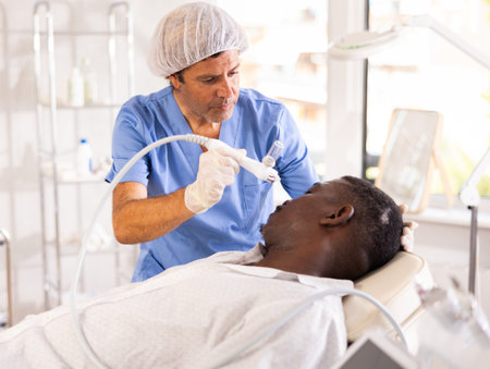 Aesthetician applying atomized nutrients onto black man face