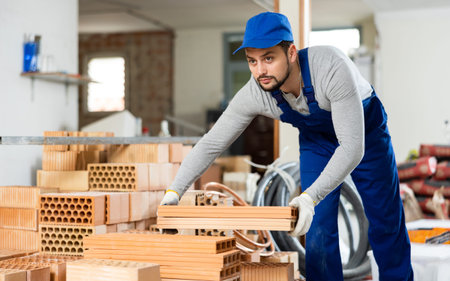 Young man stacking bricks at construction site