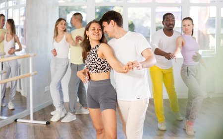 Group of men and women in sportswear learning to dance latin dances in dance studio