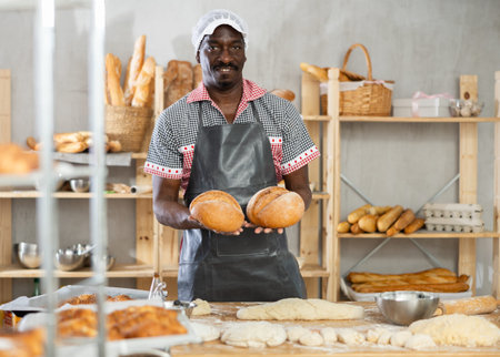 Successful African American baker holding freshly baked bread