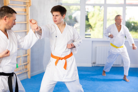 Young guy and his coach practice punches in karate sparring in gymの写真素材