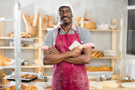 Portrait of male baker with knife for cutting dough in interior of private bakeryの写真素材