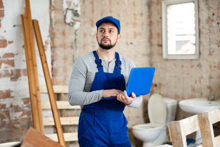 Builder handyman checking plan of house renovation on laptop