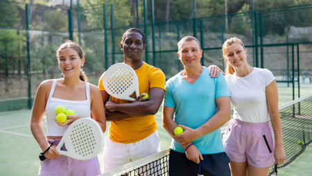 Two pairs of padel players are happily discussing past game on an open courtの写真素材