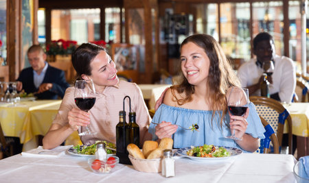 Two best friends have fun talking at a table in restaurant