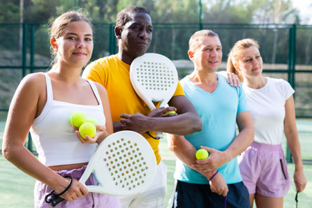 Two pairs of padel players are happily discussing past game on an open courtの写真素材