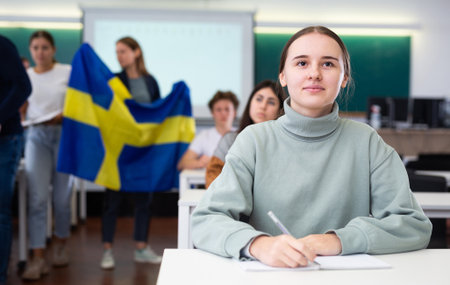 Teacher stands behind students with flag of Swedenの写真素材