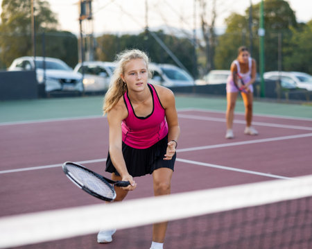 Portrait of concentrated energetic girl playing tennis, preparing to hit forehand to return ball close to netの写真素材