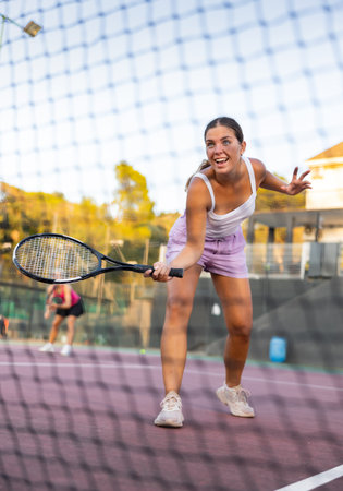 Cheerful woman tennis player training on courtの写真素材