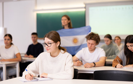Young teacher stands behind students with flag of Argentinaの写真素材