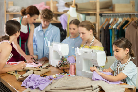 Girl learns to sew on sewing machine in class. Children learn to make pattern with their teacherの写真素材