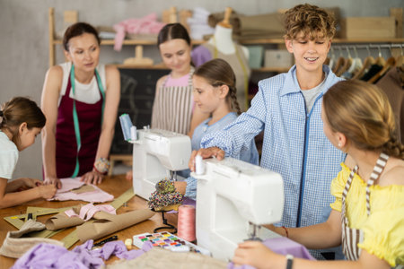 Preteen boy helping classmate thread sewing machineの写真素材