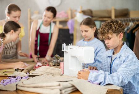 Teen boy child sews during practical lesson at school of young fashion designersの写真素材