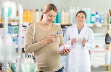 Pregnant woman buyer scans pills qr code with woman pharmacistの写真素材