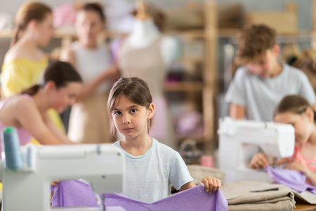 Teenage girl happily shows off a t-shirt she sewed with her own hands on sewing machineの写真素材