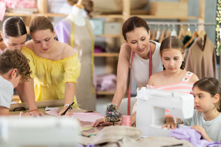 Teenage girl tries to sew on sewing machine. Teacher helps. Children watch and learn