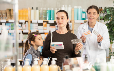 woman with a child buys medicines at a pharmacy with a pharmacistの写真素材