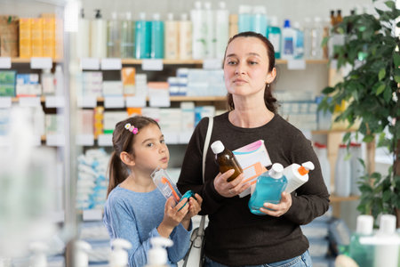 Woman with small daughter customers in drugstore buy different productsの写真素材