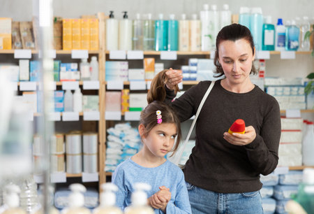 Woman chooses remedy for treating itchy scalp in childの写真素材