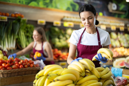 Woman seller putting bananas on the counterの写真素材