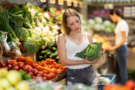 Woman choosing green cabbage in grocery storeの写真素材