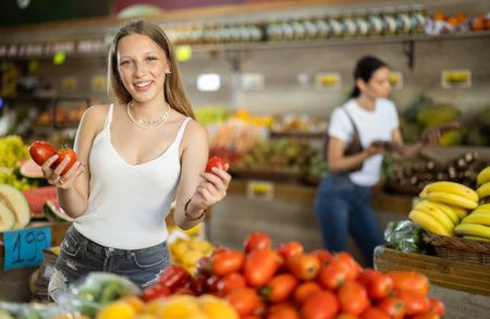 Young woman standing in store and holding tomatoesの写真素材