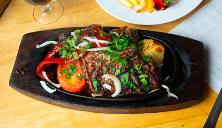 Baked pieces of beef with potato and vegetables in wooden plateの写真素材