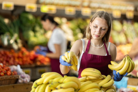 Woman seller putting bananas on the counterの写真素材