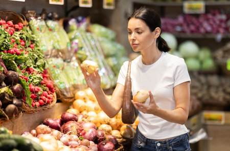 Young woman choosing onions in the vegetable departmentの写真素材