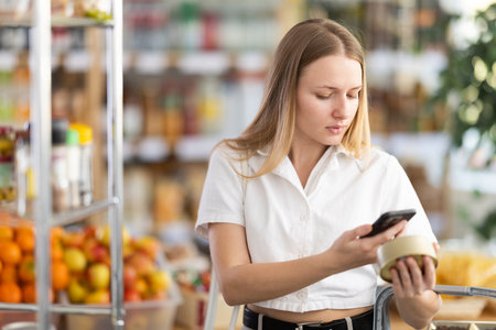 Young woman scanning qr code of canned foodの写真素材