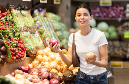 Young woman choosing onions in the vegetable departmentの写真素材