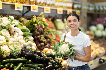 Woman shopping in grocery supermarket choosing broccoli cabbageの写真素材