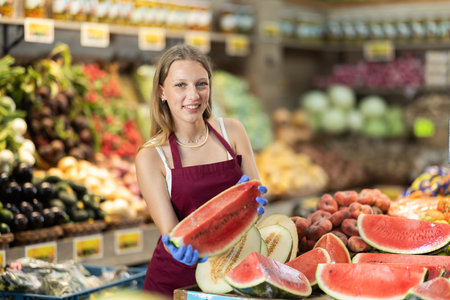 Young woman seller putting watermelon in vegetable shopの写真素材