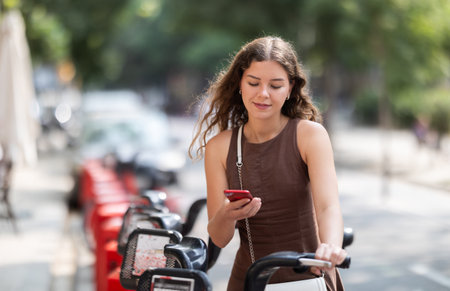 Woman with mobile phone in her hands near bicyclesの写真素材