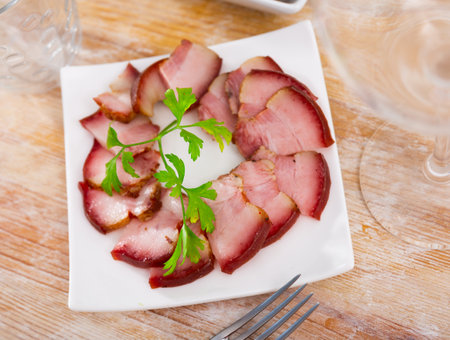 Smoked lard cut with herbs on white plateの写真素材
