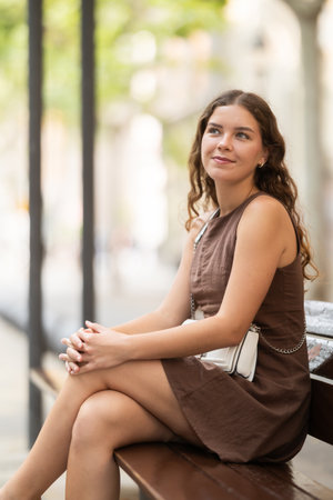 Young woman sitting on a bench in a European cityの写真素材