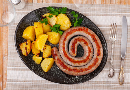 Fried potatoes and traditional spanish pork sausage butifarra on plateの写真素材