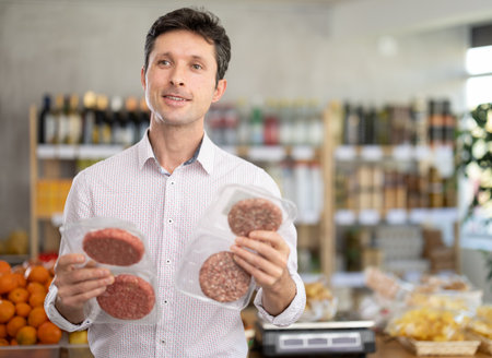 man chooses packages of hamburger pattiesの写真素材