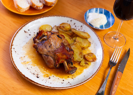 Portion of pork knuckle with boiled potatoes and gravy in plateの写真素材