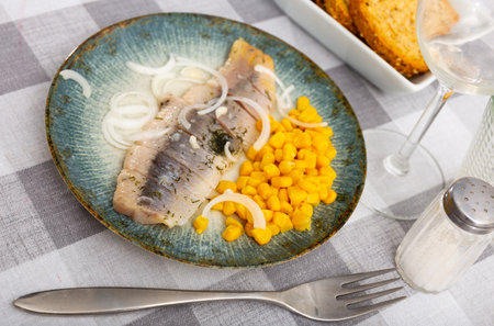 Slices of spicy marinated herring fillet with corn and onionの写真素材