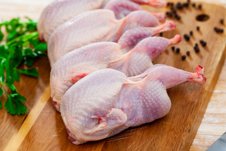 Home cooking. Fresh raw gutted quails and condiments prepared for roasting on wooden table..の写真素材