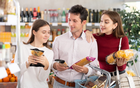 Couple man and woman with girl choosing pasta in groceryの写真素材