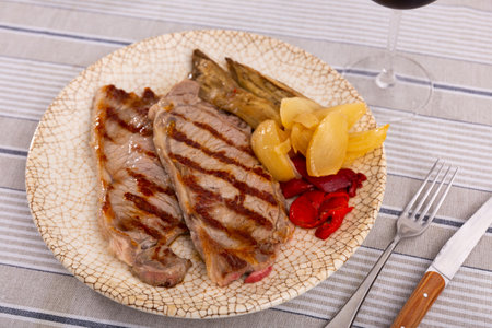Delicious mediterranean style steak served with baked tomatoes calcot onion and tomatoesの写真素材