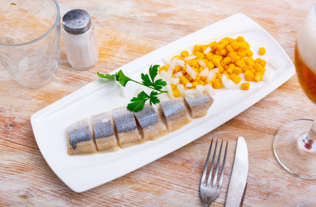 Slices of spicy marinated herring fillet with corn and onionの写真素材