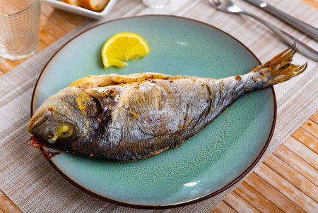 Dorada fish served on plate with lemonの写真素材