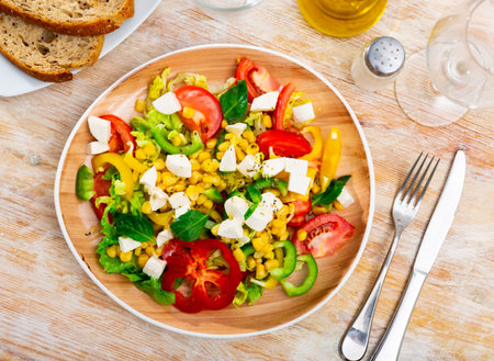 Delicious light vegetable salad of tomatoes, canned corn, pepper and Feta cheeseの写真素材