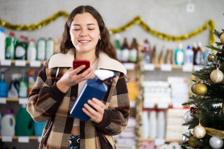 In Christmas decorated shop, woman client scanning QR code on package paint removerの写真素材